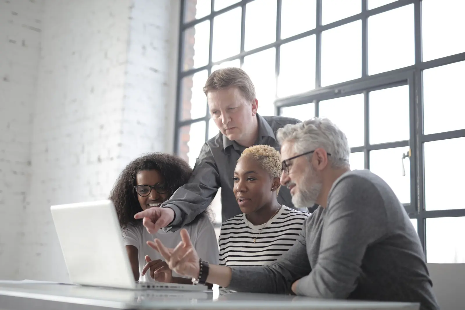 A person explaining their work on a laptop to a small group.
